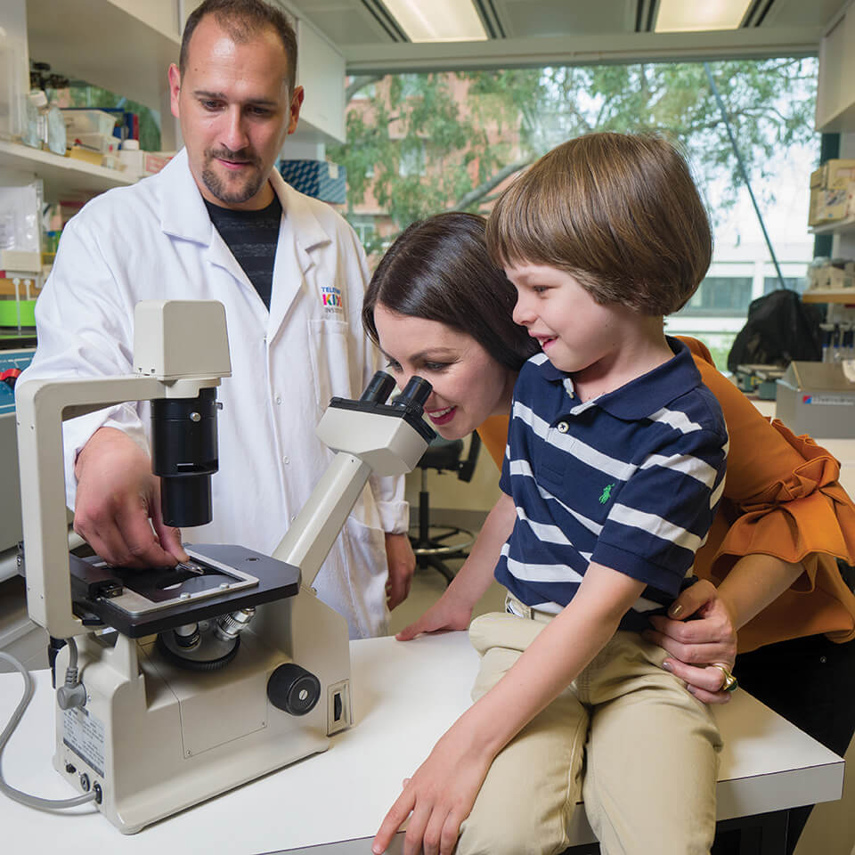 Researcher Anthony Bosco takes philanthropist Sarah D’Onofrio and son Samuel through some of his work